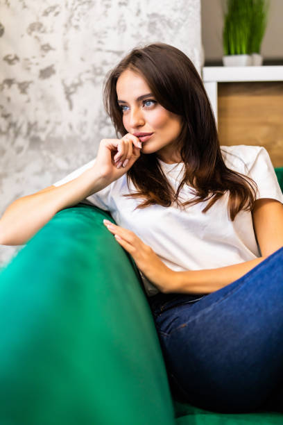 istock . Attractive young woman sitting on sofa at home 1287328126