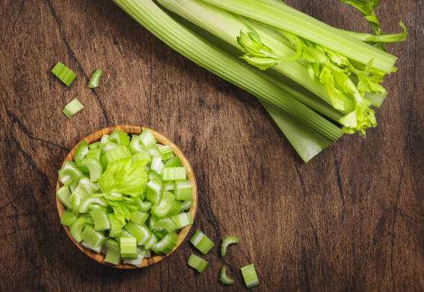 istock Green celery chopped pieces in bowl, wooden table, top view, copy space 1287331632