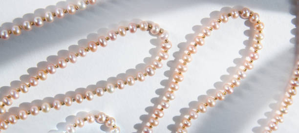 istock Pink pearl necklace background with hard shadows. Top view. 1287331995