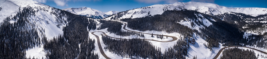 Stitched aerial panorama of a mountain road winding through the Rocky Mountains in Grand County, Colorado, near the town of Winter Park.