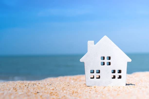 cerrado pequeños modelos domésticos en la arena con la luz del sol y el fondo de la playa. - tangram casa fotografías e imágenes de stock