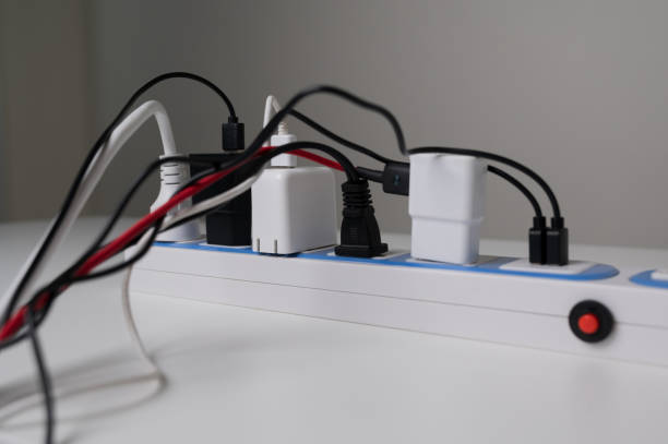 istock Risk of electric shock Overload. Many electric cable plugged in socket. Electrical equipment, electrical wires and power strips on the wall. 1287344315
