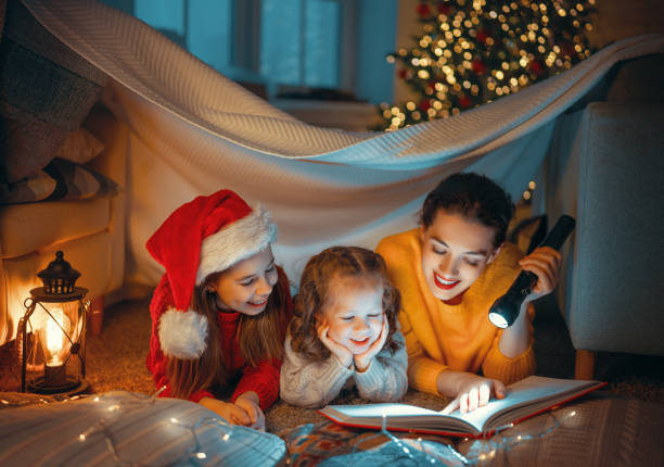 istock mother reading book to daughters near Christmas tree 1287350394