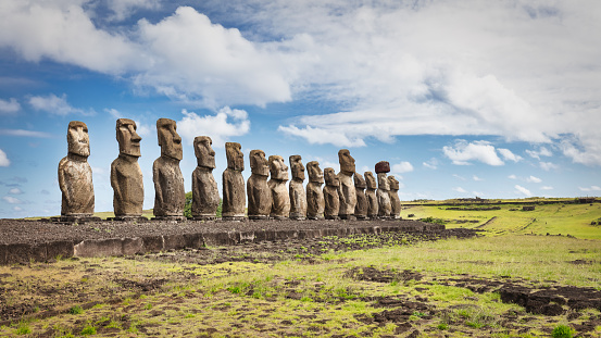 Easter Island Ahu Tongariki Panorama. Fifteen ancient civilization polynesian Moai Statues standing side by side in a row along the pacific ocean coast under sunny blue summer sky with fluffy cloudscape. Rapa Nui. Easter Island, Isla de Pascua, Polynesia, Chile, Oceania