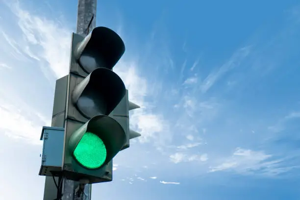 Photo of Traffic light in green color, with a blue sky and cloud in the background. Left side