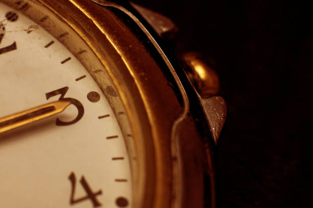 The hands on the clock at three o'clock in the afternoon close up, in red