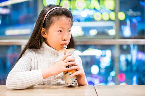 Cute Asian little girl drinking milk tea