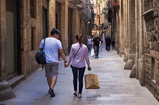 BARCELONA, SPAIN - MAY 15, 2017: Unknown young coiple walking in the Carrer de Montcada street in historical Gothic quarter of Barcelona.
