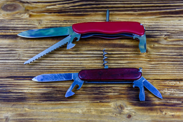 Two unfolded all purpose red pocket knives on wooden background