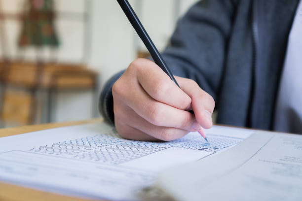 istock Hand Student use pencil writing on paper optical form of standardized test examination, Answer sheet,doing final exam attending in examination classroom 1287363765