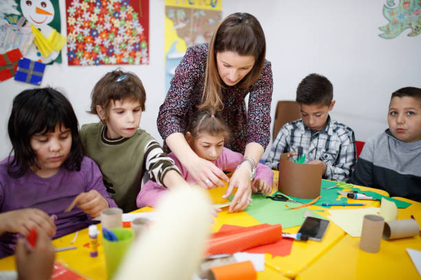 istock Special education teacher assisting elementary students with paper craft in art class 1287364005