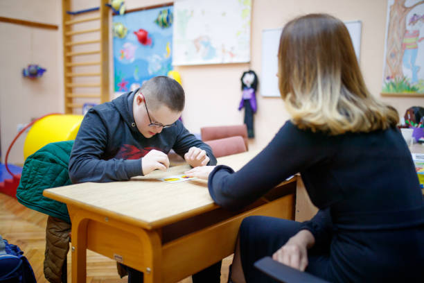 istock Female speech therapist helping a special needs teen boy 1287364046