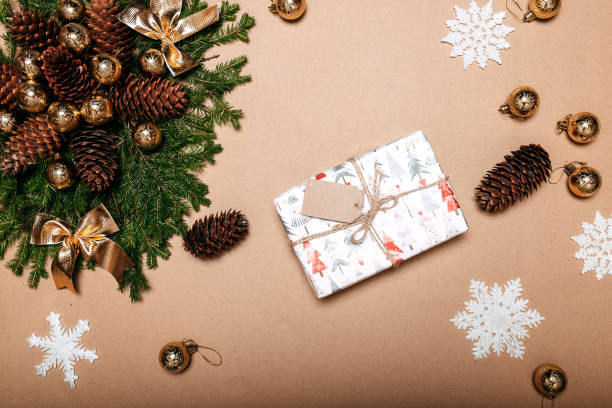 istock Christmas decorations flat layout with fir branches, snowflakes, golden balls, pine cones and gift box on the cardboard background. Gift with empty tag. 1287364193