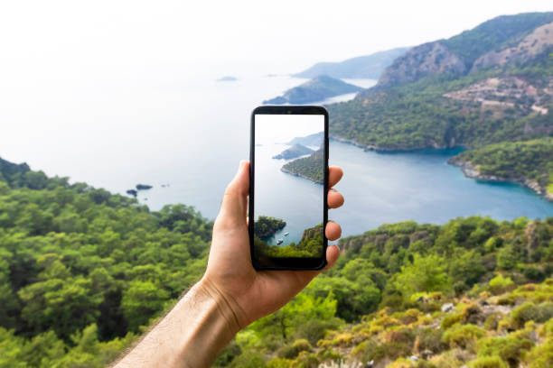 A hand with a smartphone taking pictures of the natural landscape, sea and mountains on a journey. Phone, internet and mobile network concept. Impressions and Adventures. A hand with a smartphone taking pictures of the natural landscape, sea and mountains on a journey. Phone, internet and mobile network concept. Impressions and Adventures. personal perspective photos stock pictures, royalty-free photos & images