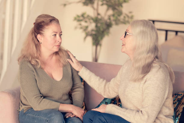 istock cute charming young female visiting her middle aged mother, sitting together on comfortable couch, having good conversation. Woman in her forties talking to daughter at home 1287366841