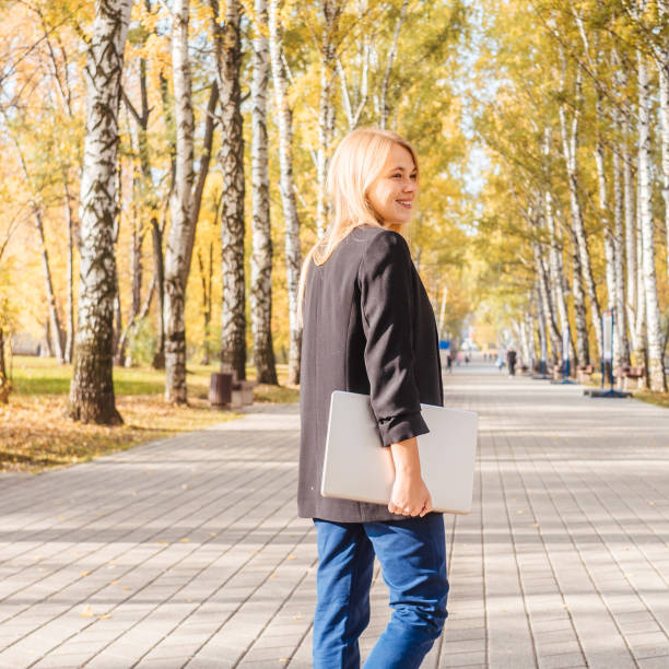 istock Young woman hold laptop in park 1287367473