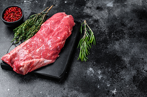 Raw flank beef meat steak. Black background. Top view. Copy space.