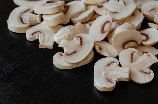istock Group of raw champignons cut into pieces on black background. 1287367995