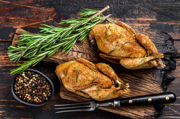 Homemade baked quail on a cutting board.  Dark Wooden background. Top view Homemade baked quail on a cutting board.  Dark Wooden background. Top view. celebrity roast stock pictures, royalty-free photos & images