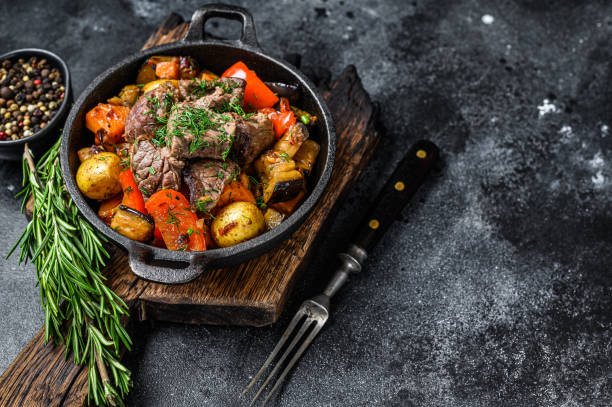 istock Meat stew in cooking pot on dark rustic cutting board. Black background. Top view. Copy space 1287370251