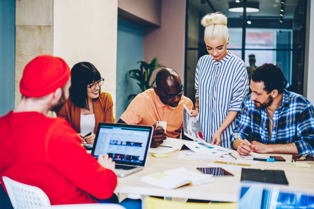 istock Multicultural group of creative young people collaborating on discussing graphic sketches during brainstorming.Diverse male and female employees in smart casual wear cooperating in modern office 1287374500