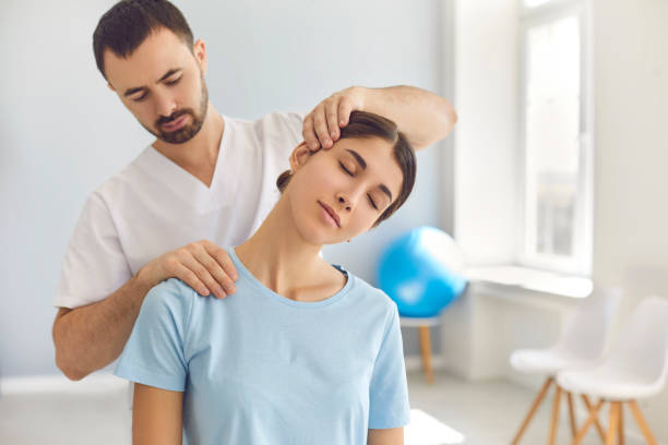 Licensed chiropractor doing neck adjustment to female patient in modern medical office Licensed chiropractor or manual therapist doing neck stretch massage to relaxed female patient in clinic office. Young woman with whiplash or rheumatological problem getting professional doctor's help osteopath photos stock pictures, royalty-free photos & images