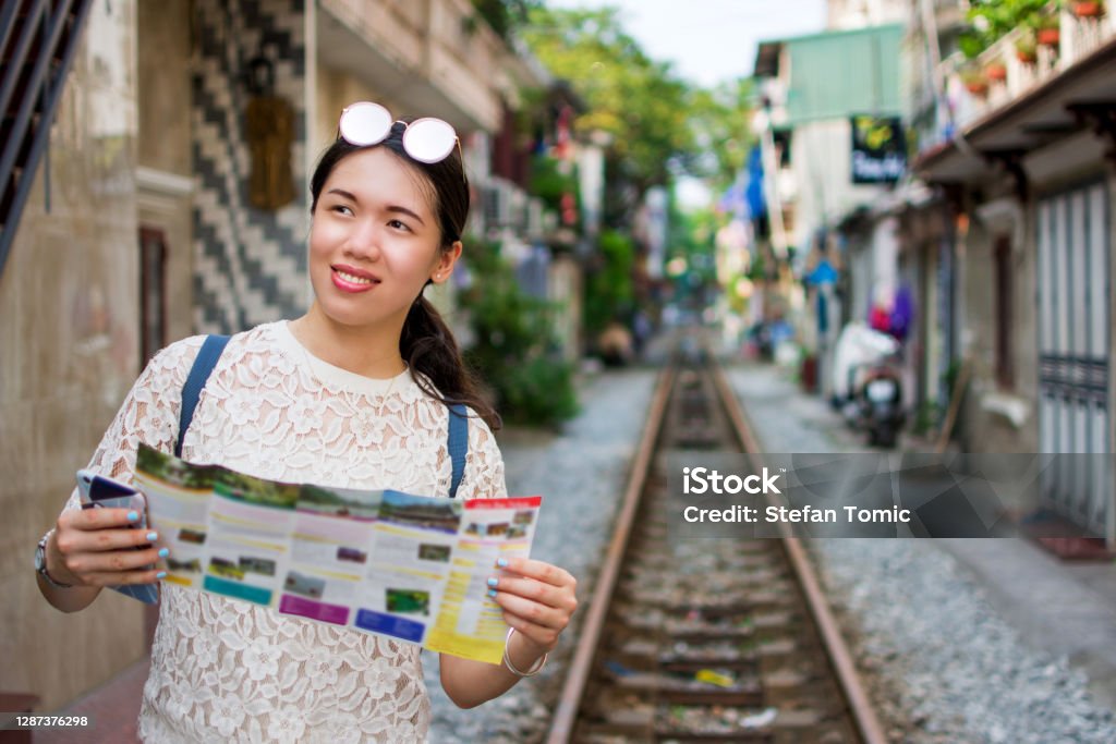 Female tourist in the Hanoi train street, Vietnam Asian woman visiting the train street in Hanoi Vietnam and holding a travel map, South East Asia travel and wanderlust abstract Adult Stock Photo