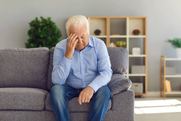 istock Depressed senior man sitting on sofa at home suffering from loneliness or bad headache 1287376363