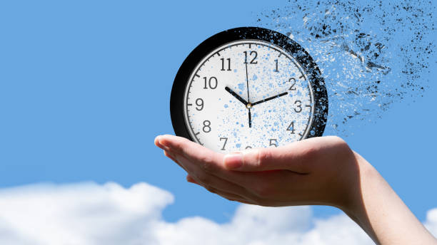 時間の終わりまたは時間の概念の飛行。小片に落ちる古典的な丸時計を保持する女性の手 - time clock watch futuristic clock hand ストックフォトと画像