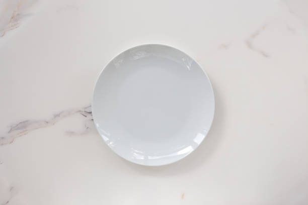 istock Empty ceramics plate isolated on white marble background. Copy space. Menu Recipe Concept 1287383893