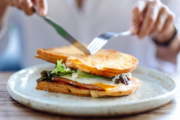 istock a woman eating ham cheese sandwich 1287385441