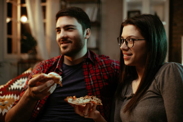 istock Happy couple eating pizza at home. 1287385586