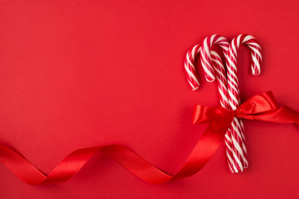 surprise savoureuse pour le concept de noël. dessus au-dessus de la fin aérienne vers le haut de la photo de flatlay des cannes dures de sucrerie enveloppées avec le ruban lumineux d’isolement au-dessus de la table lumineuse de couleur - hard candy candy mint wrapped photos et images de collection