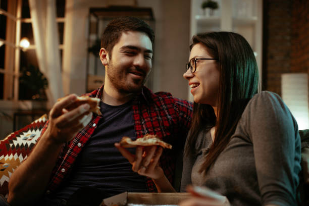 istock Happy couple eating pizza at home. 1287386835