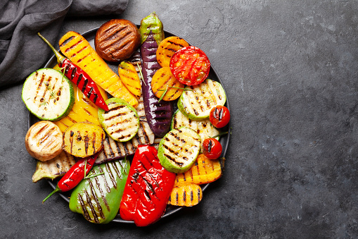 Grilled vegetables on plate with spices and herbs. Top view flat lay with copy space