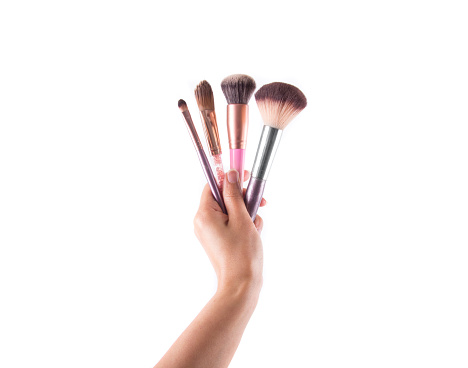 Makeup brushes in female hand on white background