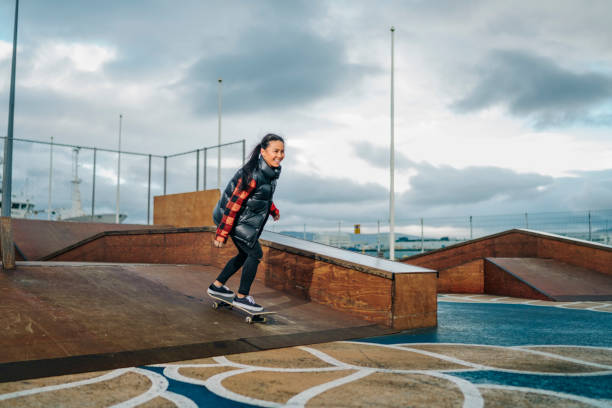 istock Smiling woman skateboarding on ramp at park 1287389206