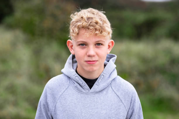 Headshot of a Caucasian Teenage Boy A portrait shot of a caucasian teenage boy in a rural outdoor setting looking at the camera with a contented emotion and wearing a hooded sweatshirt. 12 13 years stock pictures, royalty-free photos & images