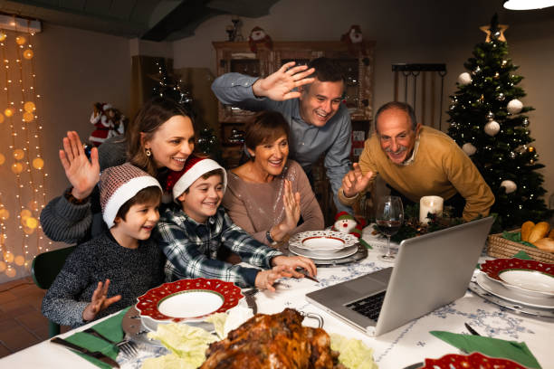 Video call during Christmas eve. Happy and Excited family greeting their family and friends on Christmas eve using a skype video call during the coronavirus pandemic. Some relatives waving and talking to a laptop. Social distancing. thanksgiving holiday covid stock pictures, royalty-free photos & images