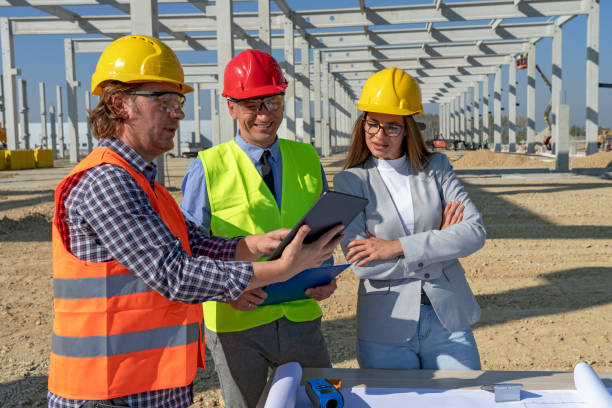 istock Construction Foreman in Yellow Hardhat Holding Digital Tablet and Discuss a Project With Female Architect and Businessman 1287393316