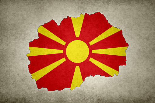 Grunge map of North Macedonia with its flag printed within its border on an old paper.