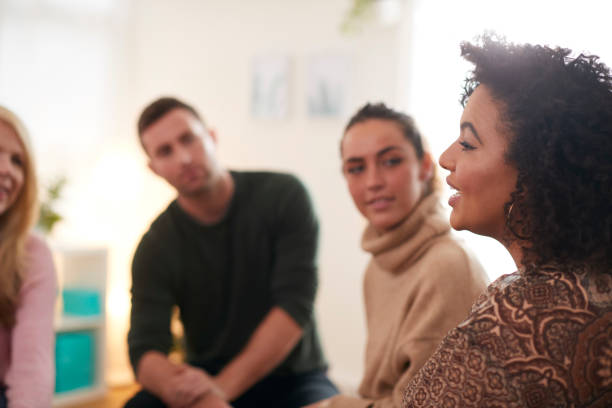 Woman Speaking At Support Group Meeting For Mental Health Or Dependency Issues In Community Space Woman Speaking At Support Group Meeting For Mental Health Or Dependency Issues In Community Space group of people stock pictures, royalty-free photos & images