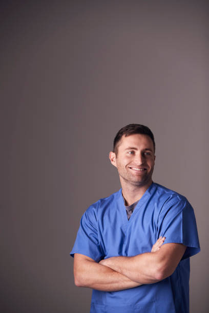 Studio Portrait Of Male Nurse Wearing Scrubs Standing Against Grey Background Studio Portrait Of Male Nurse Wearing Scrubs Standing Against Grey Background porter photos stock pictures, royalty-free photos & images