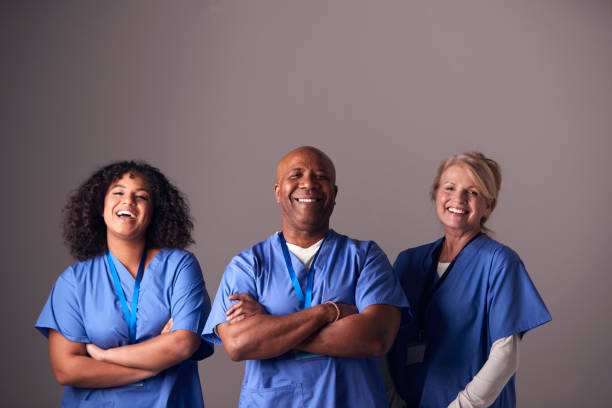 회색 배경에 서 스크럽을 입고 외과 팀의 세 멤버의 스튜디오 초상화 - 간호사 뉴스 사진 이미지
