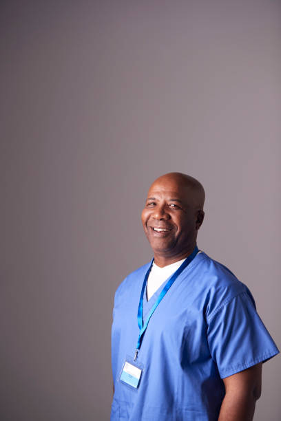 Studio Portrait Of Male Nurse Wearing Scrubs Standing Against Grey Background Studio Portrait Of Male Nurse Wearing Scrubs Standing Against Grey Background porter photos stock pictures, royalty-free photos & images