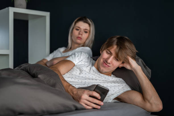 istock Young couple lying in bed and using a mobile phone 1287396330