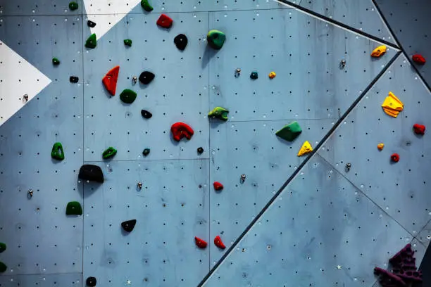 Photo of Climbing wall close-up view with color grips on it