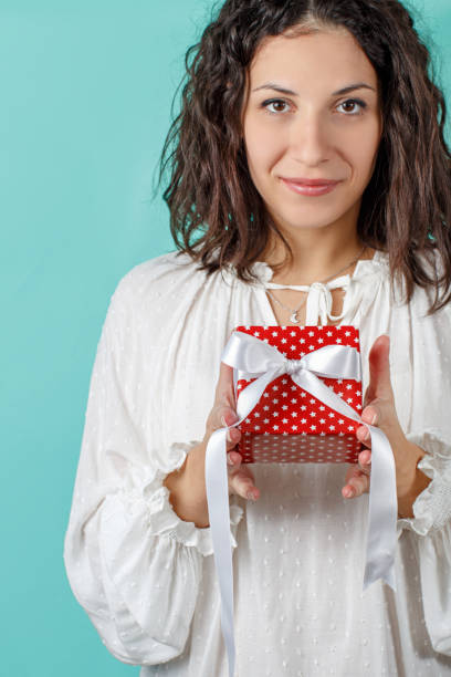 istock Young woman holding Gift package in hands close up 1287397894