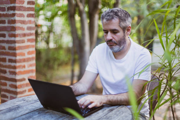 istock Remote work concept.A man works with a laptop in the garden. 1287398511