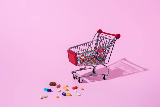 istock Creative medical layout made with pharmaceutical medicine pills, tablets, capsules in shopping trolley on pastel pink background 1287399143